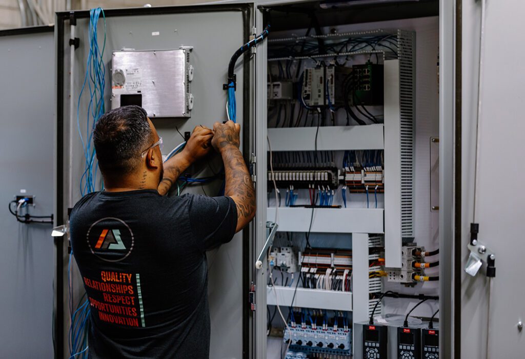A man is working on an electrical panel for Industrial Power Services.